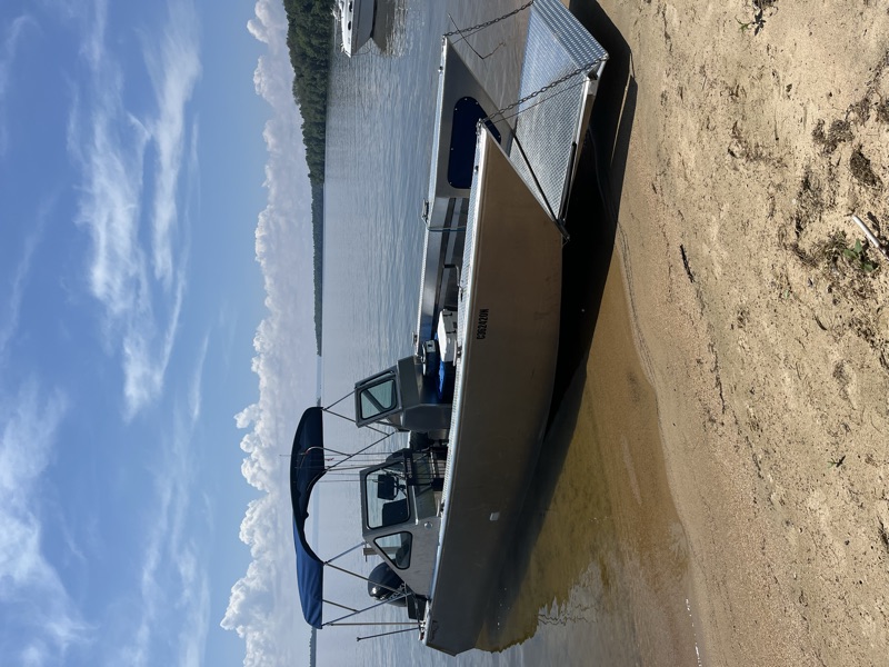 Lake Nipissing Outfitters charter boat beached on sandy shore with front gate open