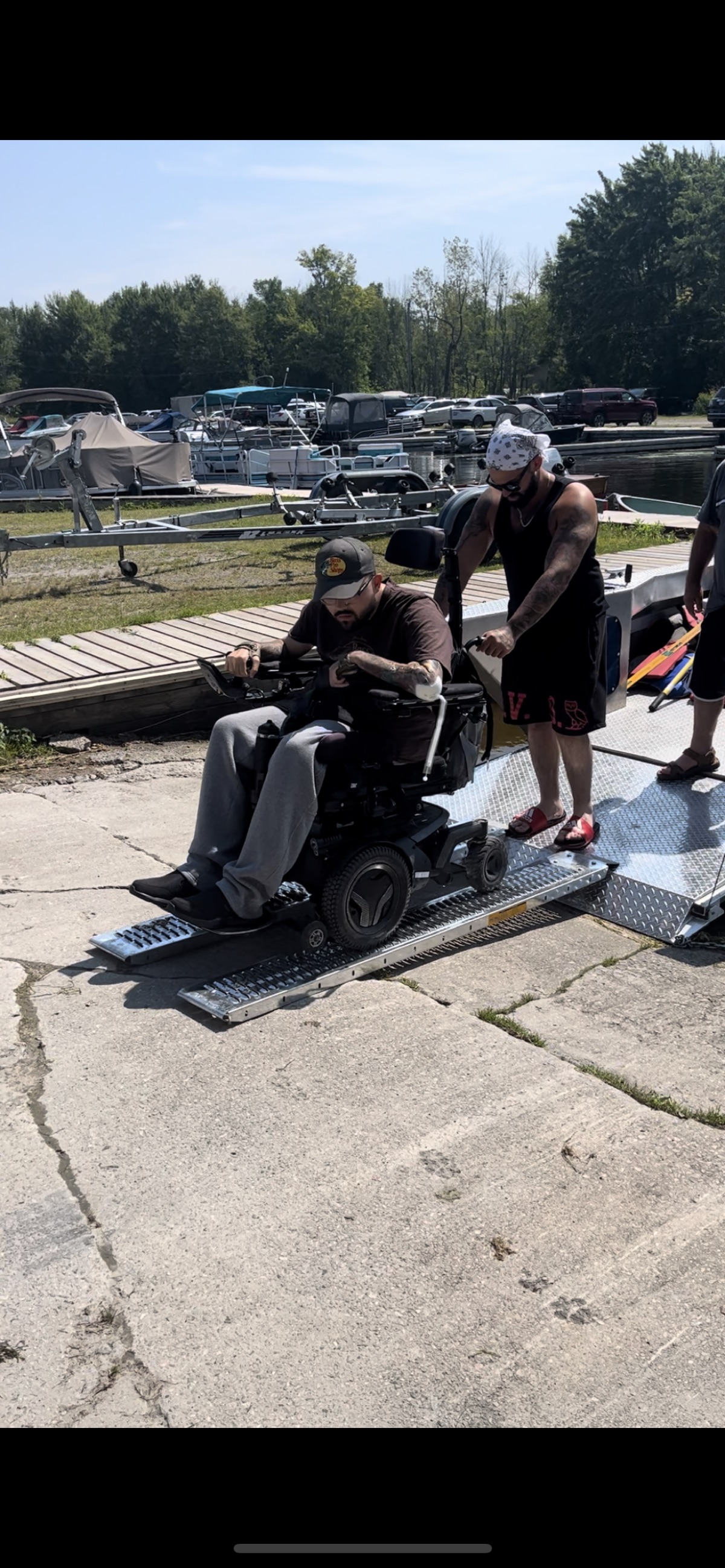 Wheelchair user being assisted onto boat ramp at the marina