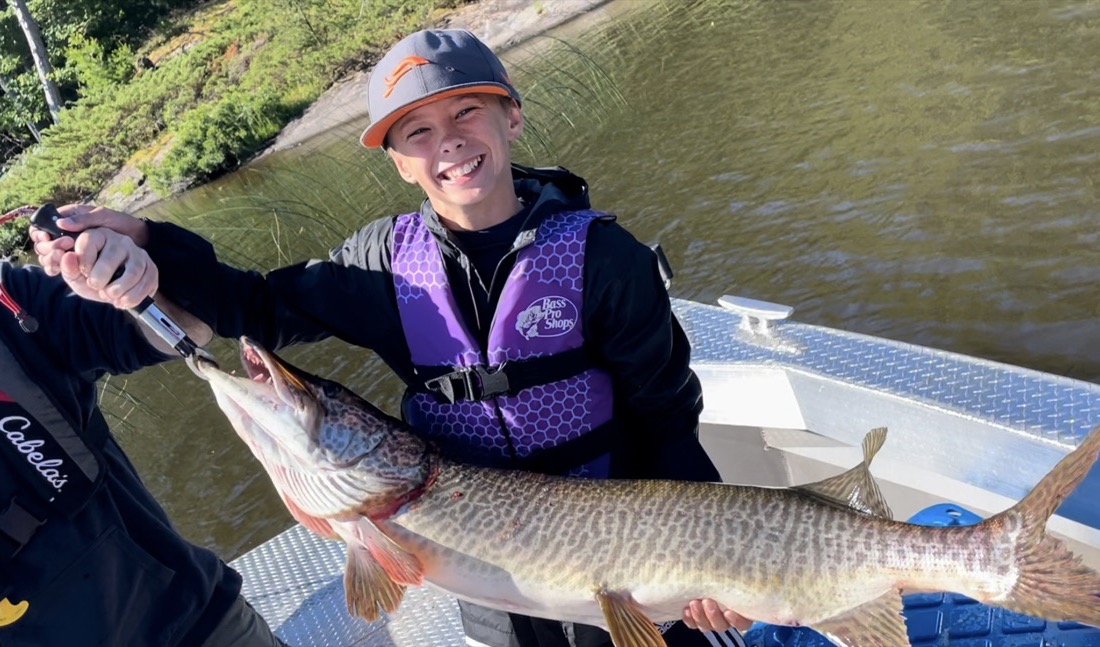 Young angler holding a large musky caught on a guided fishing trip on Lake Nipissing